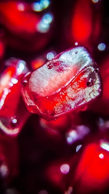 Close-up of ripe pomegranate seeds glistening under market lights.