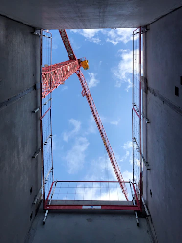 orange crane on gray concrete wall during daytime