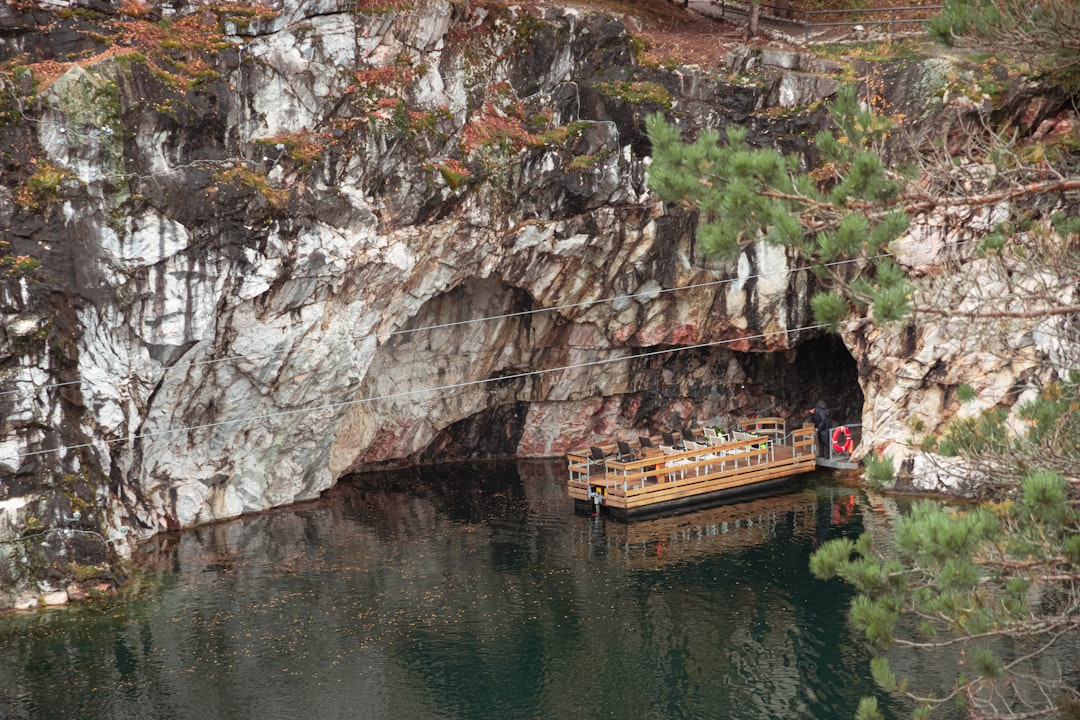 brown boat on river near brown rocky mountain during daytime