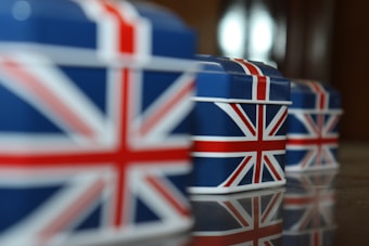 Several boxes are aligned, featuring the Union Jack design in blue, red, and white. The focus is on the vibrant colors and the reflections on the surface they are placed on.