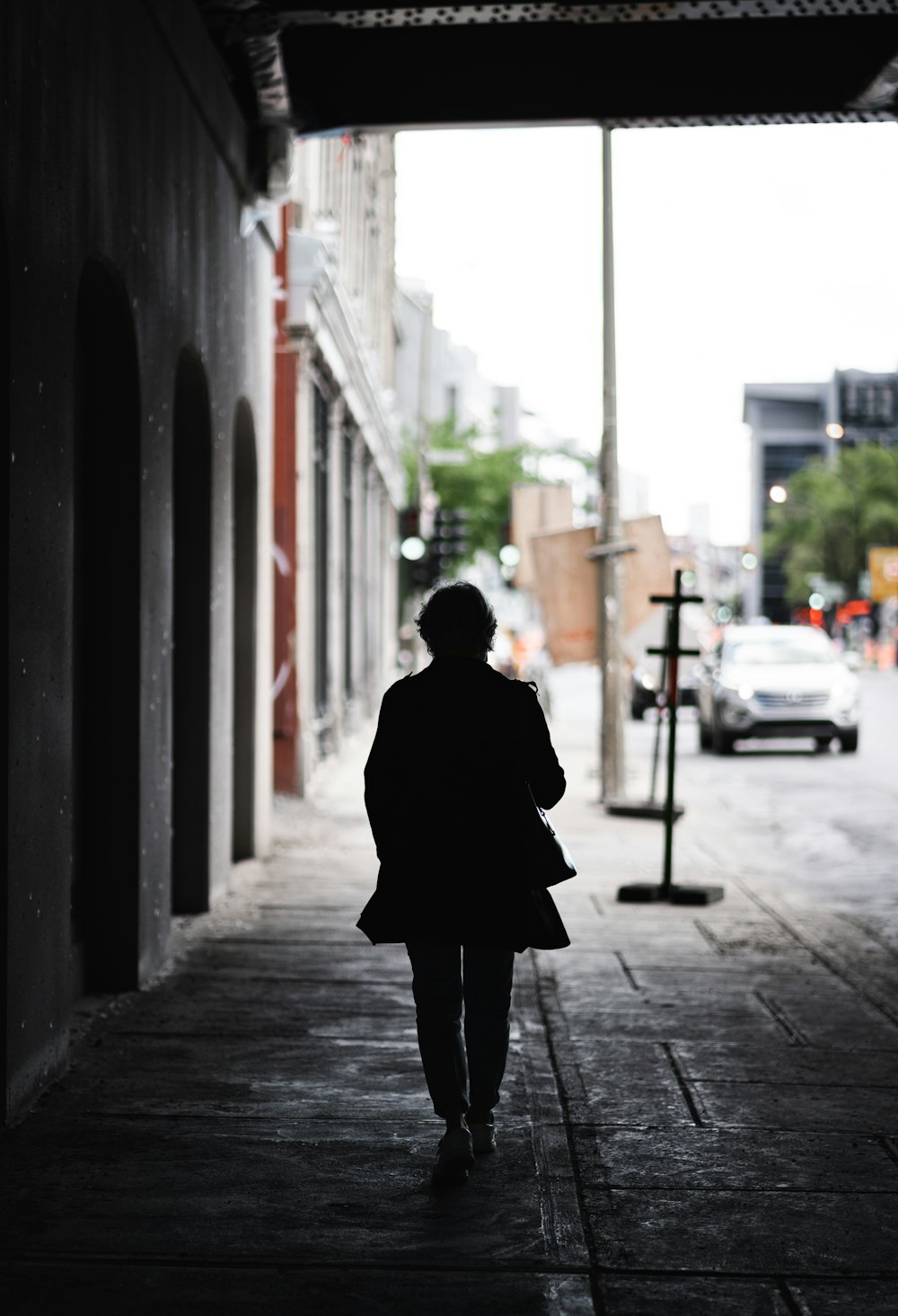 personne en manteau noir debout sur le trottoir pendant la journée