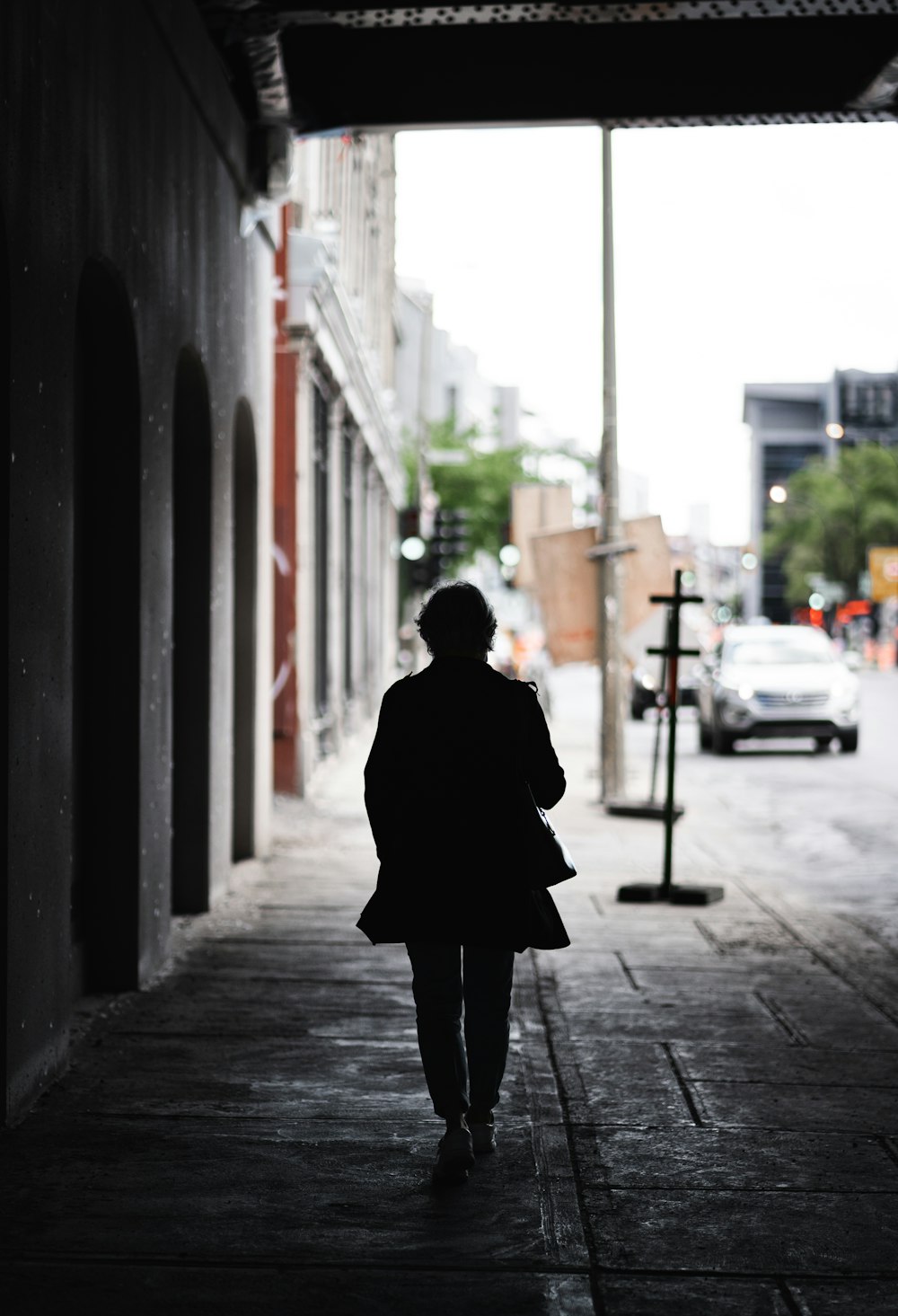 person in black coat standing on sidewalk during daytime