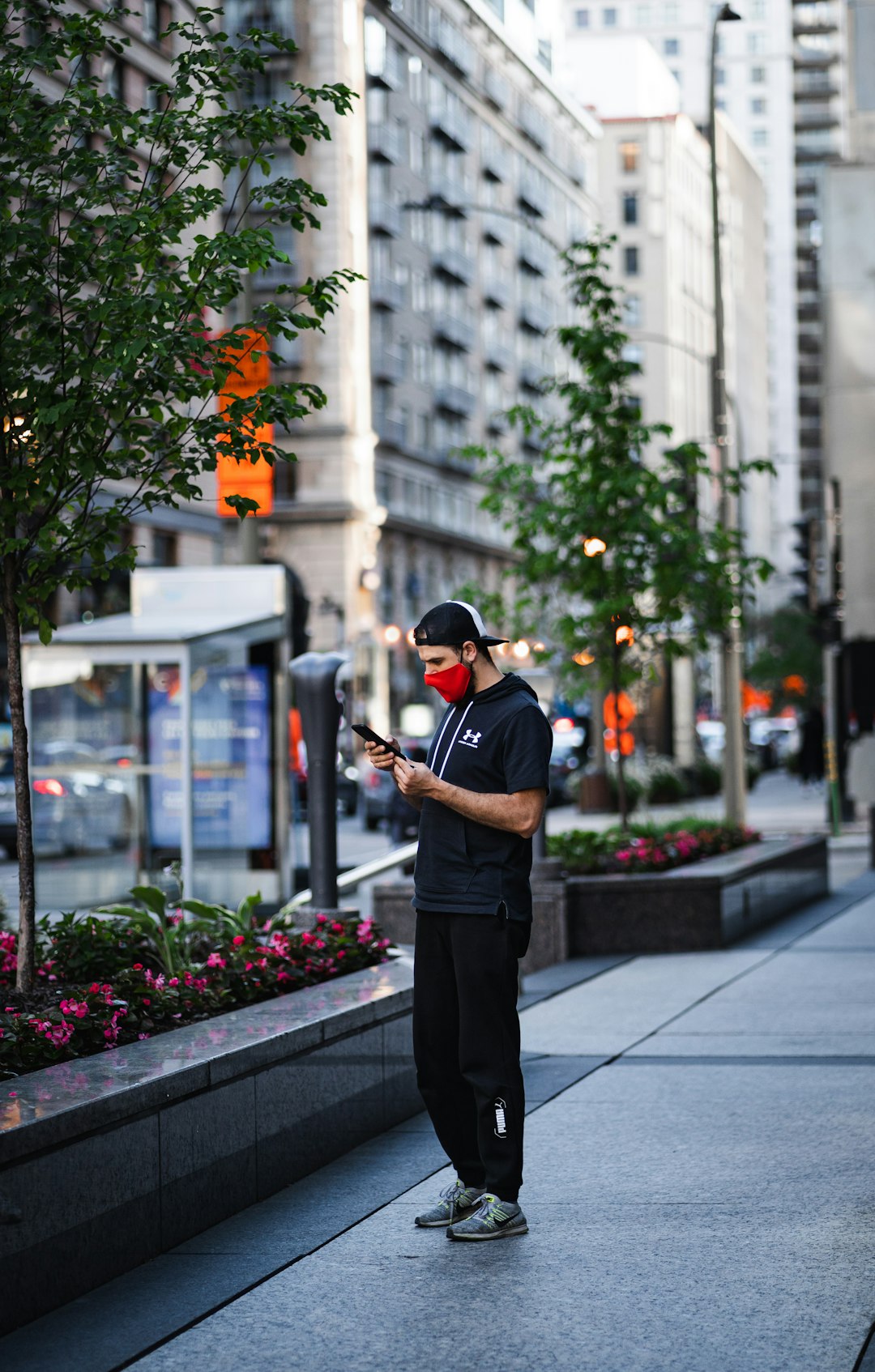 man in black t-shirt and black pants standing on sidewalk during daytime