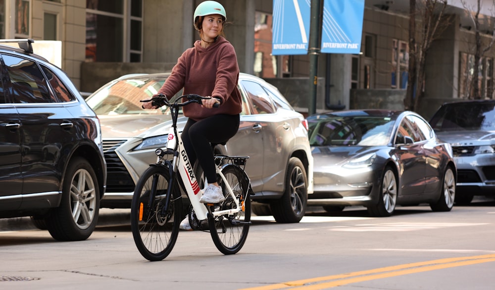 woman in brown jacket riding on bicycle during daytime