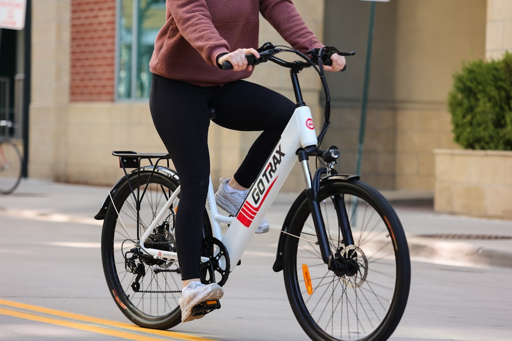 person in red jacket and black pants riding black and white bicycle