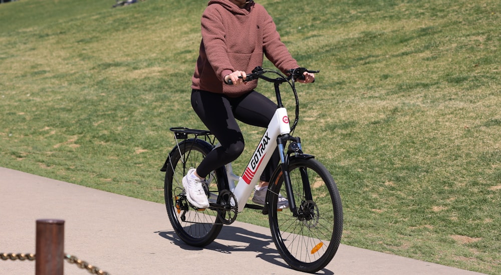 man in red jacket and black pants riding on red and white bicycle during daytime