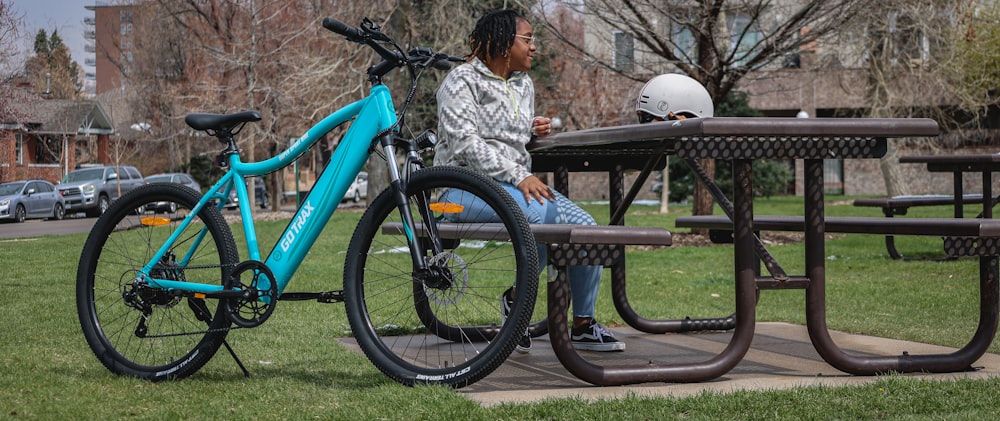 girl in white and black jacket sitting on blue bicycle during daytime