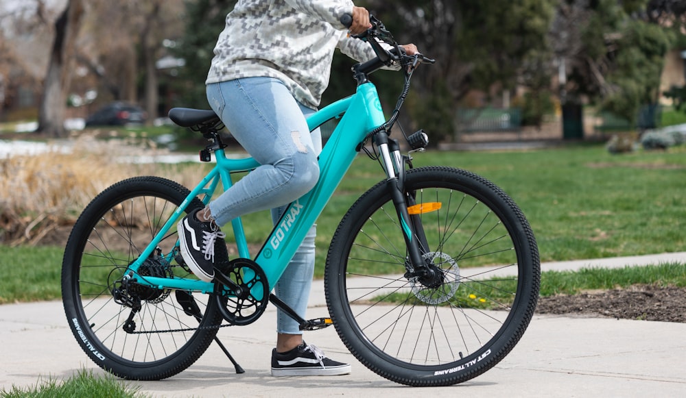 person in gray pants riding on blue bicycle