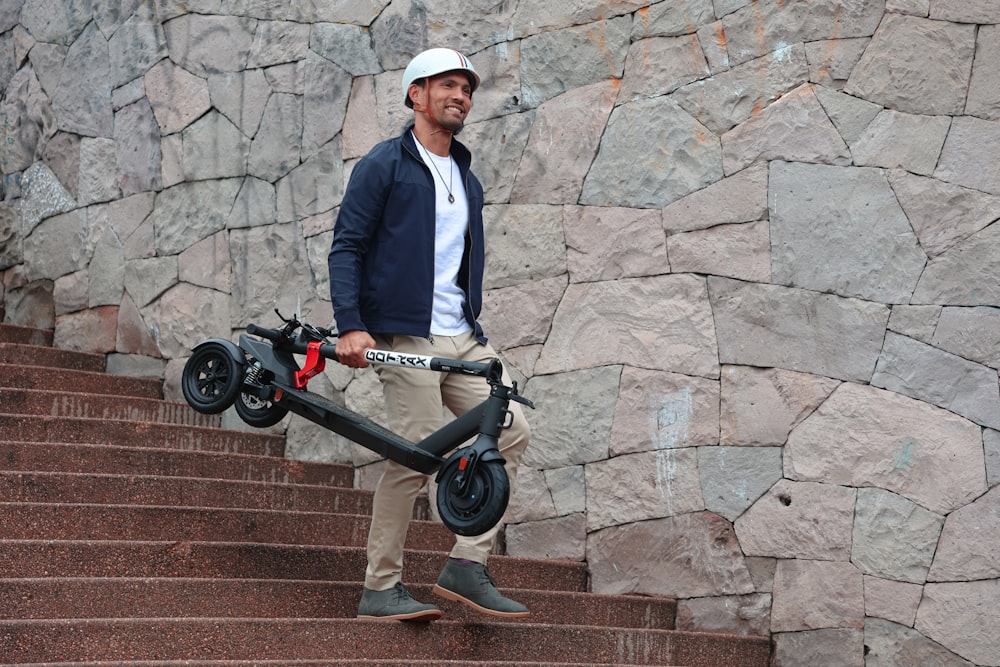 smiling man is carring a folded electric scooter in his hand