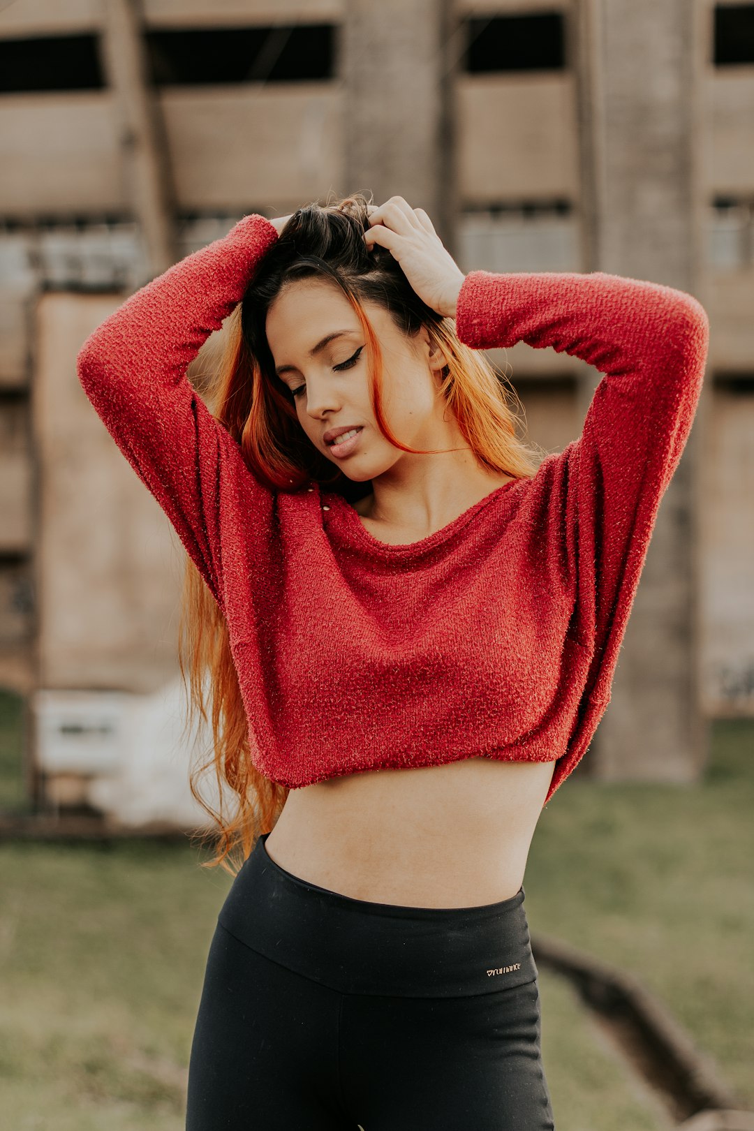 woman in red sweater standing on green grass field during daytime