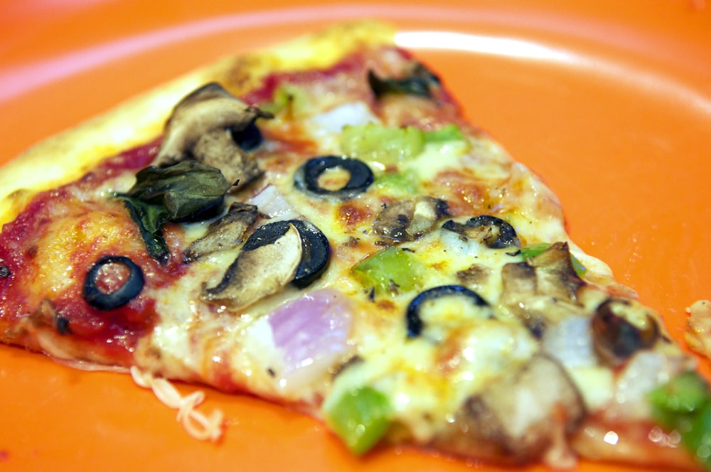 pizza with green and red vegetable on orange plate