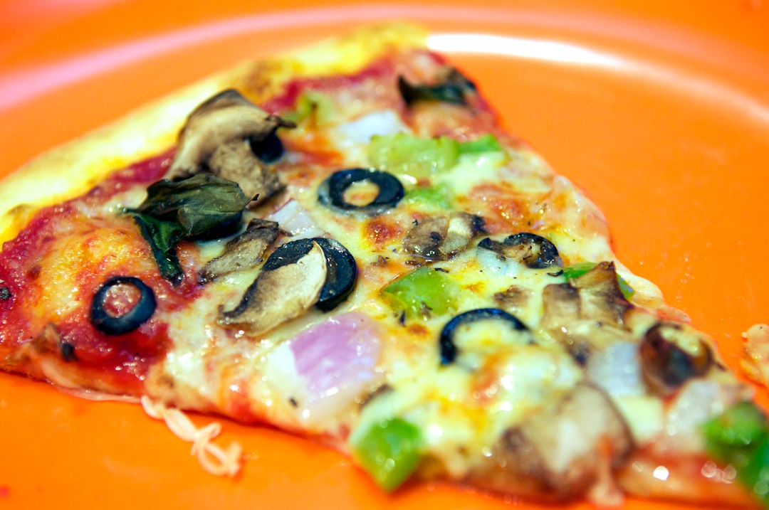 pizza with green and red vegetable on orange plate