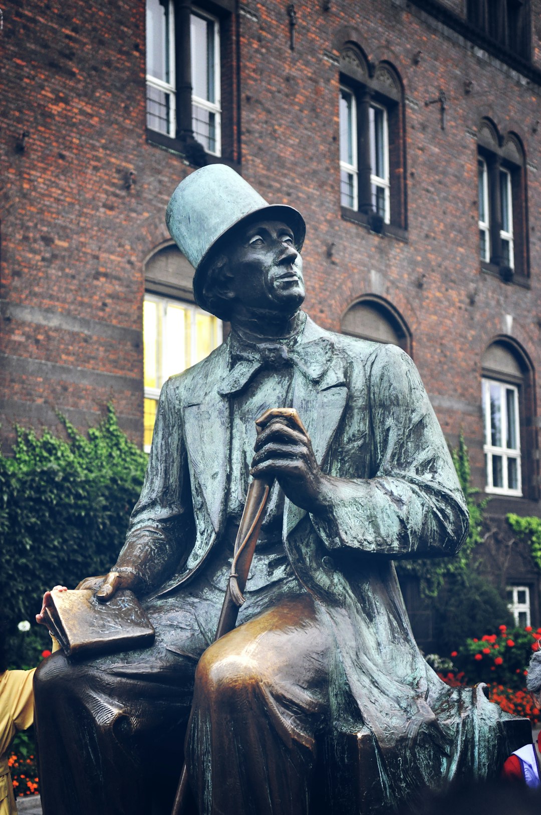 man in hat statue near brown brick building during daytime