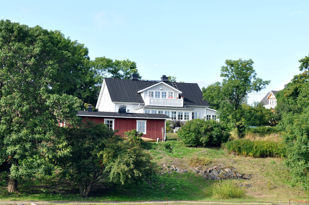 red and white wooden house surrounded by green trees under blue sky during daytime