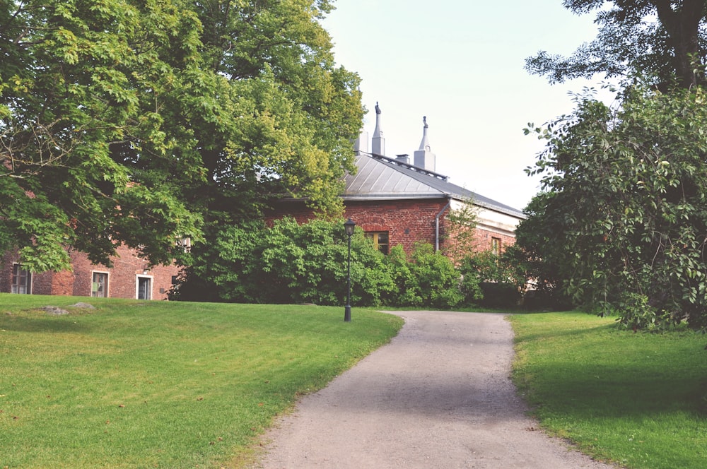 brown brick house near green trees during daytime