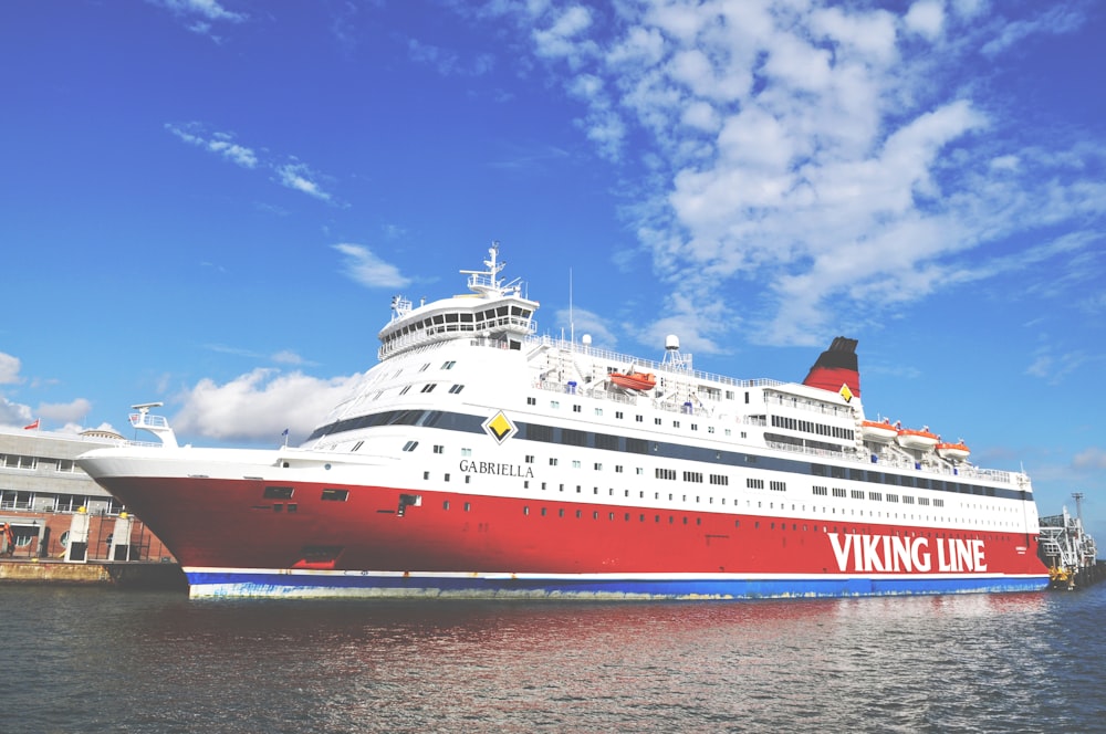 white and red cruise ship on sea under blue sky and white clouds during daytime