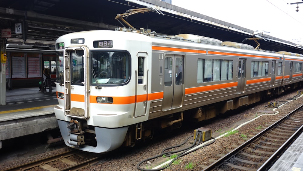 weiß-oranger und grüner Zug auf Bahngleisen