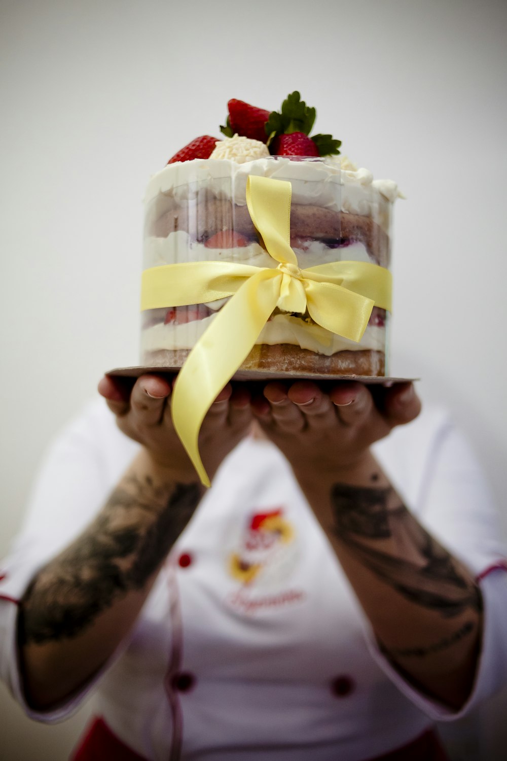 person holding white and yellow floral cake