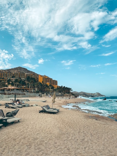 A friendly travel advisor helping a couple plan their hotel stay in a sunny Mexican beach destination.