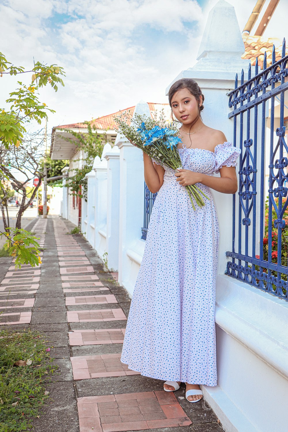 woman in blue and white polka dot sleeveless dress holding bouquet of flowers