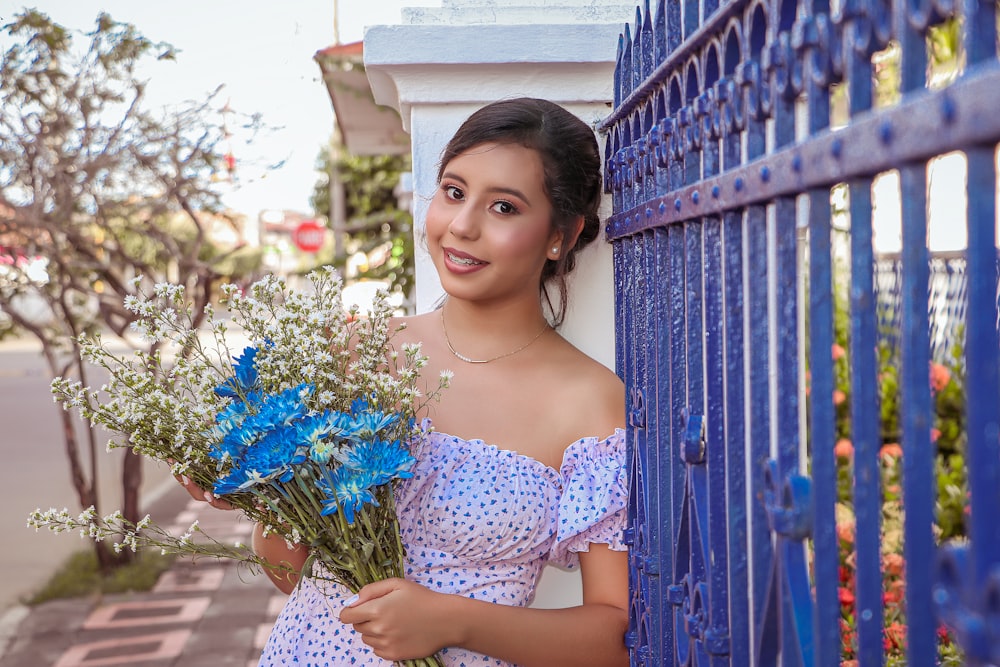 woman in blue and white floral off shoulder dress holding blue flowers