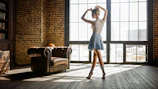 A moody editorial shot featuring a dancer poised in an industrial loft with charcoal walls.