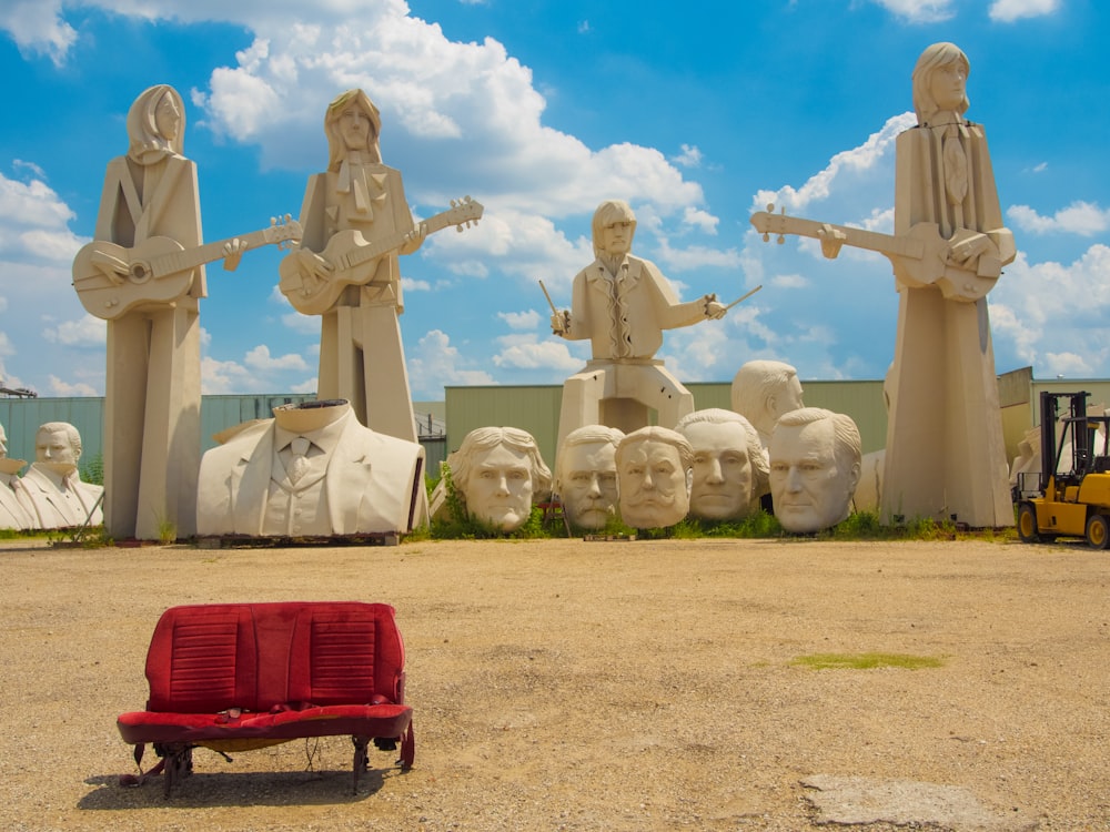 woman in white dress sitting on red bench near statue during daytime