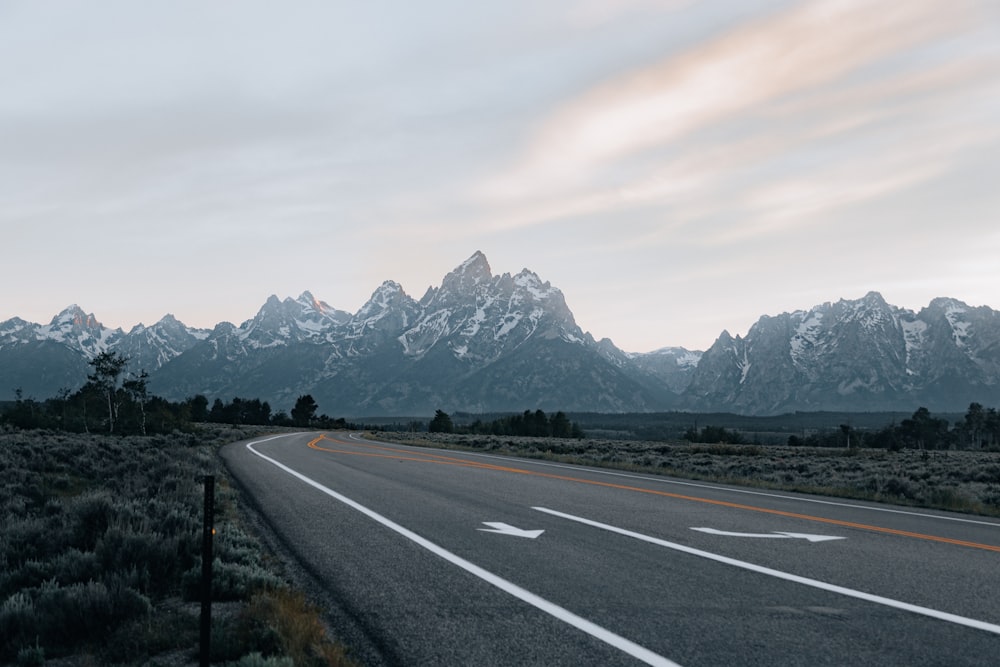 gray concrete road near mountain during daytime