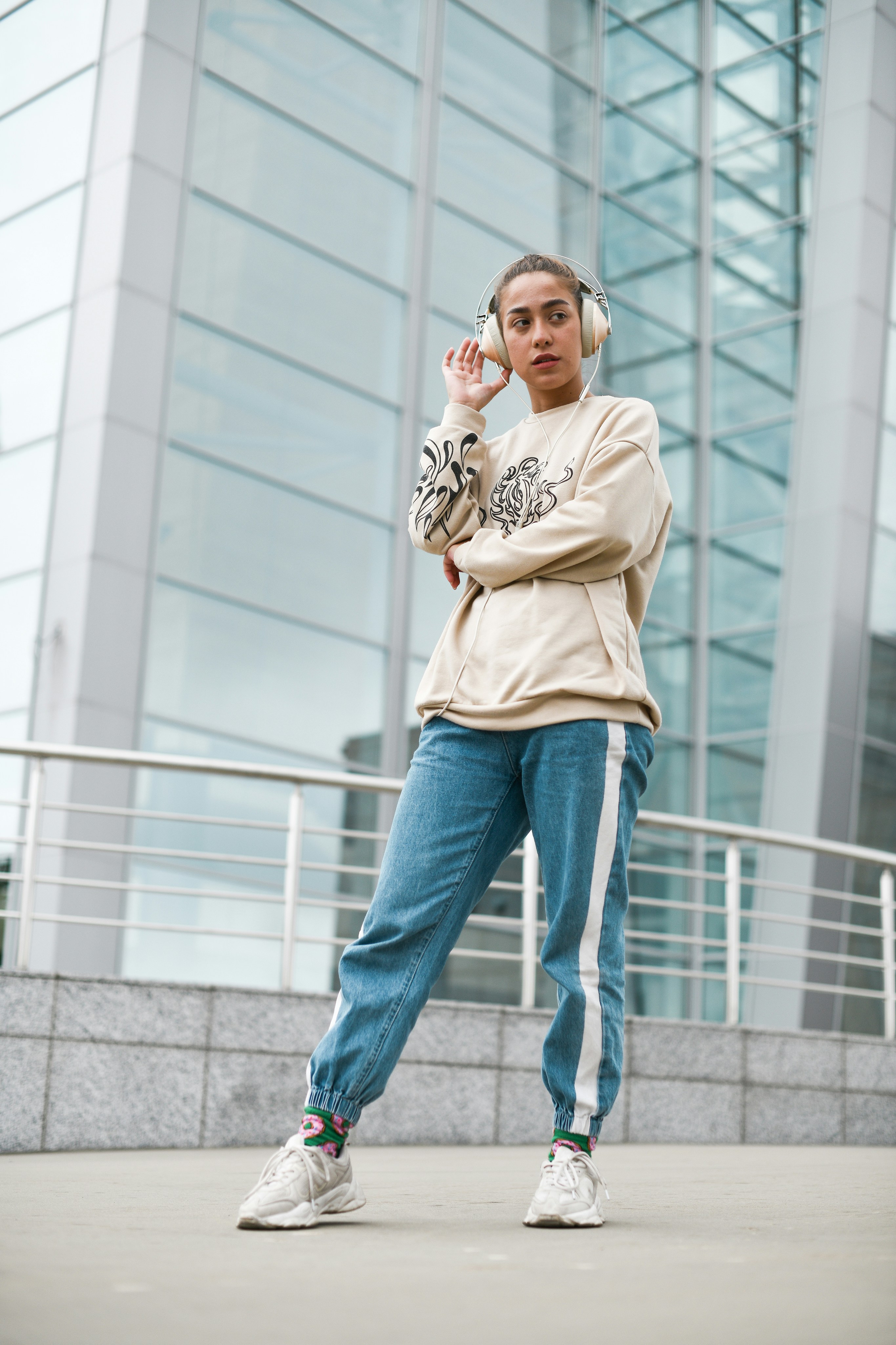 donna in t-shirt girocollo beige e jeans blu denim in piedi su scale di cemento grigio