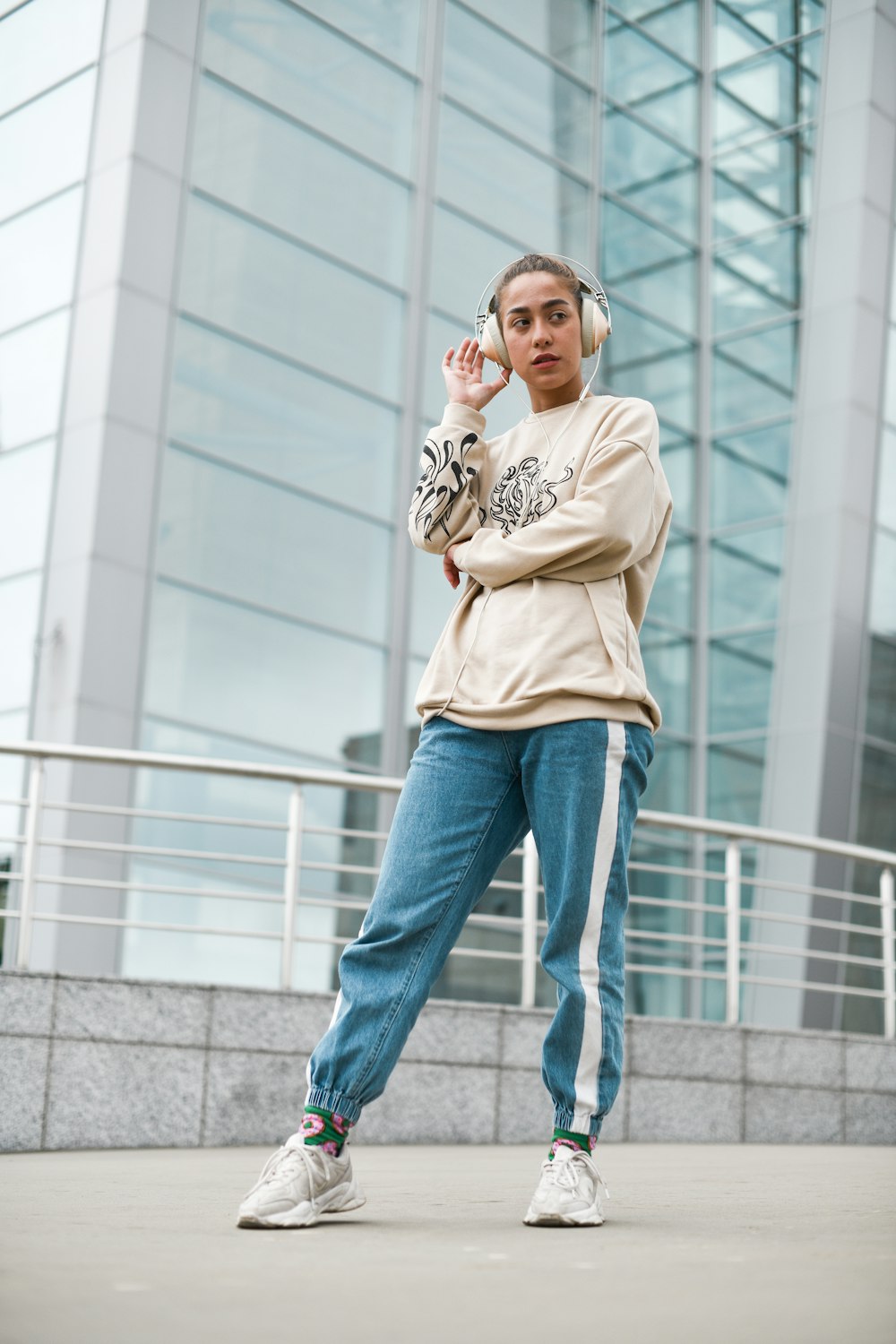 Mujer con camiseta beige de cuello redondo y jeans de mezclilla azul de pie en escaleras de concreto gris