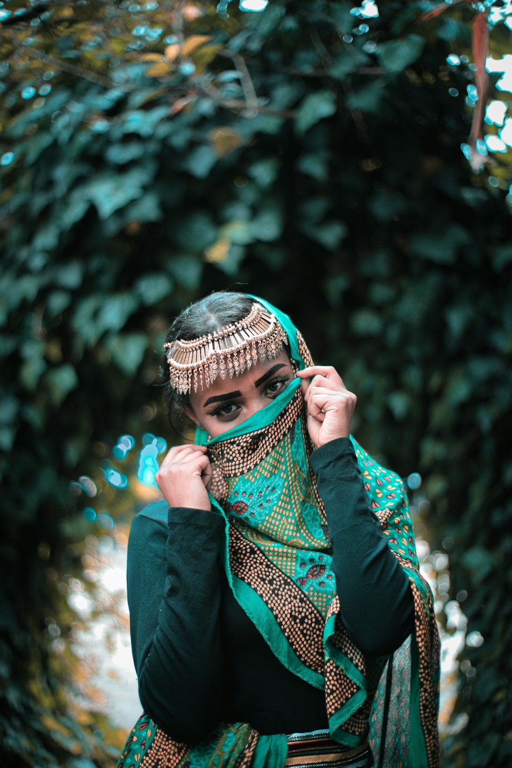 Frau im grün-weißen Hijab bedeckt ihr Gesicht mit der Hand