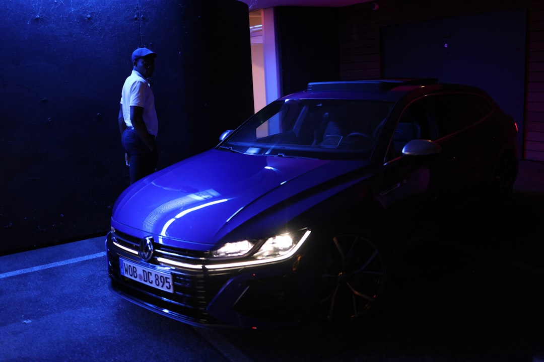 man in white shirt standing beside purple car