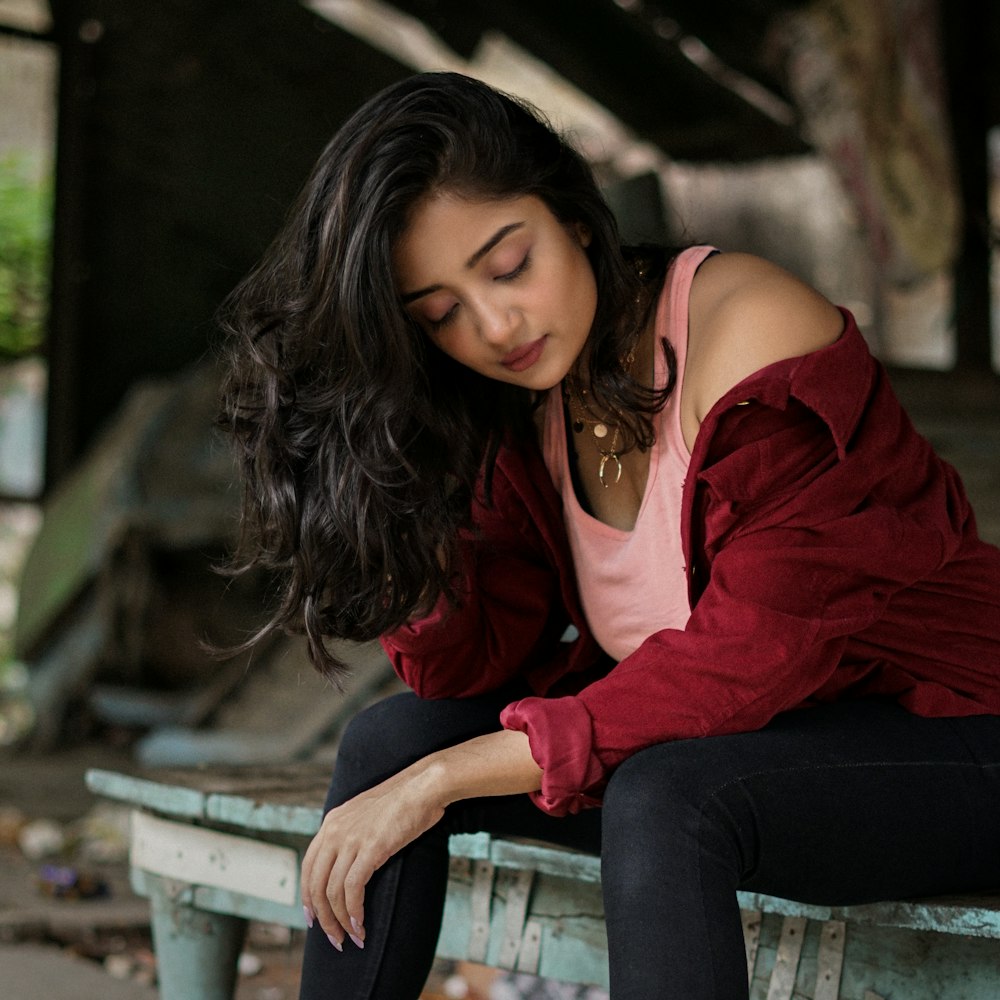 donna in camicia rossa a maniche lunghe e jeans blu in denim seduta sulla panca