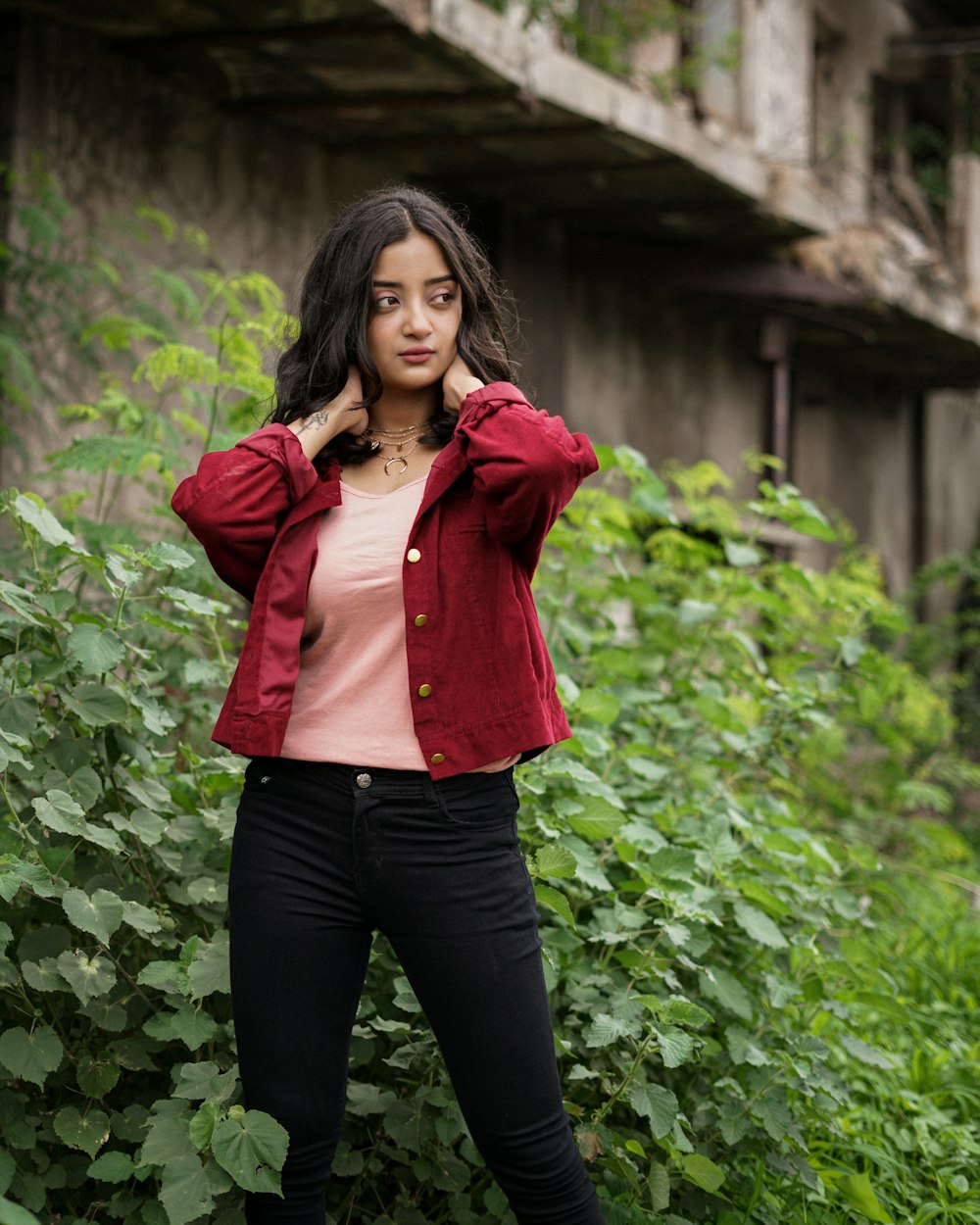 woman in red jacket standing near green plants