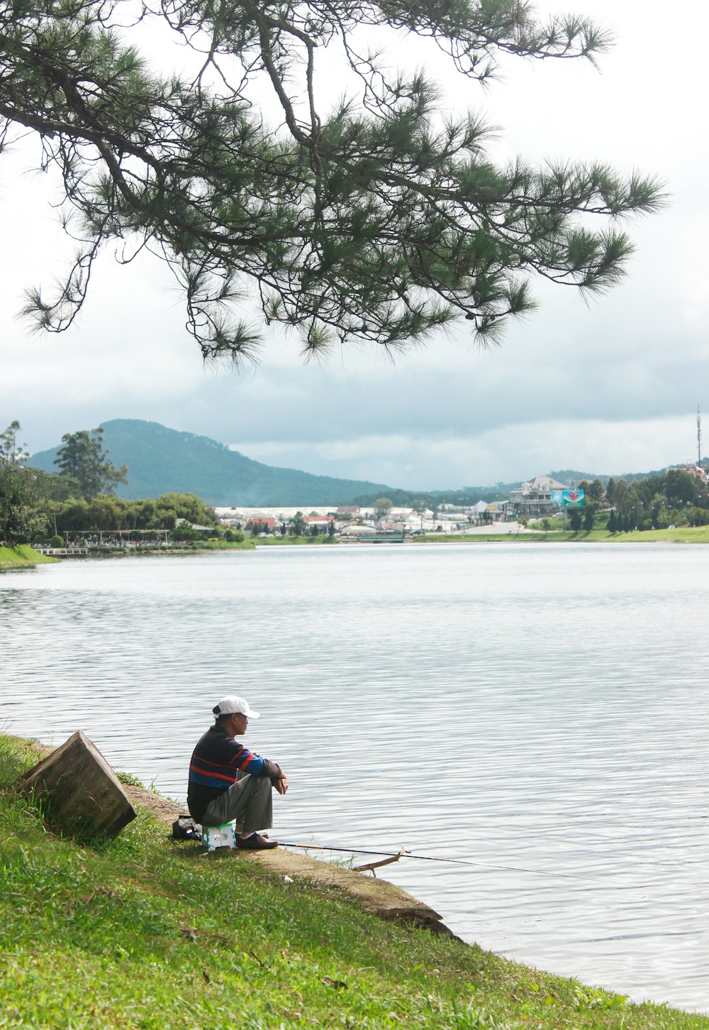 man in blue shirt sitting on brown wooden dock during daytime