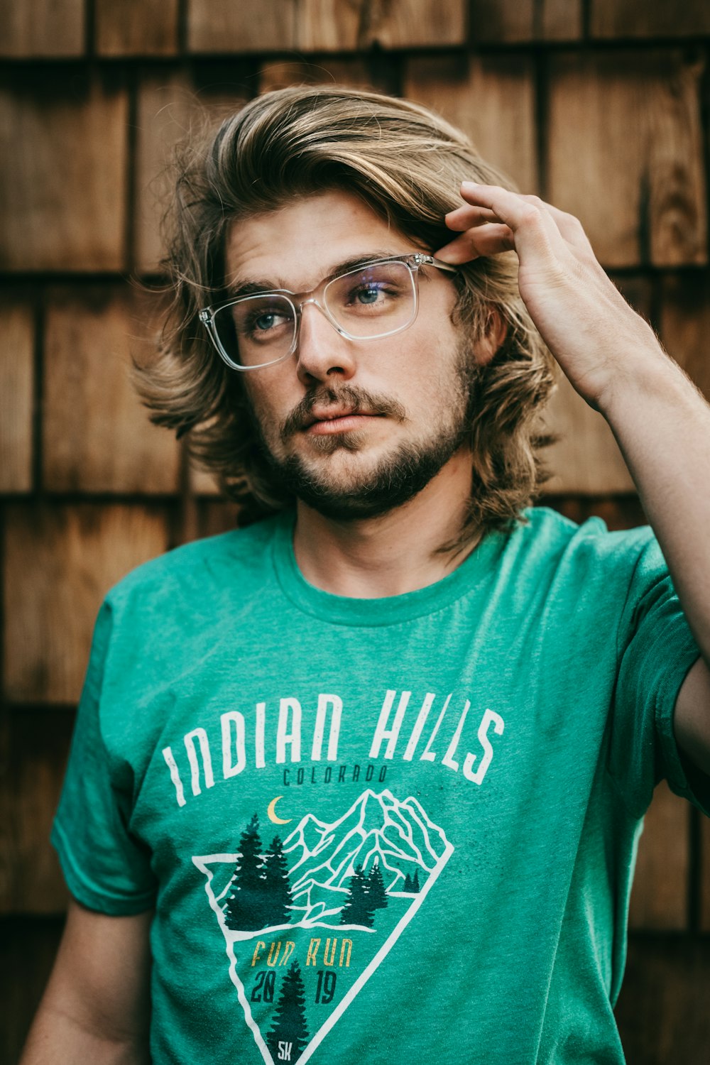 man in green crew neck t-shirt wearing black framed eyeglasses