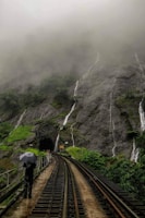 people walking on train rail near mountain