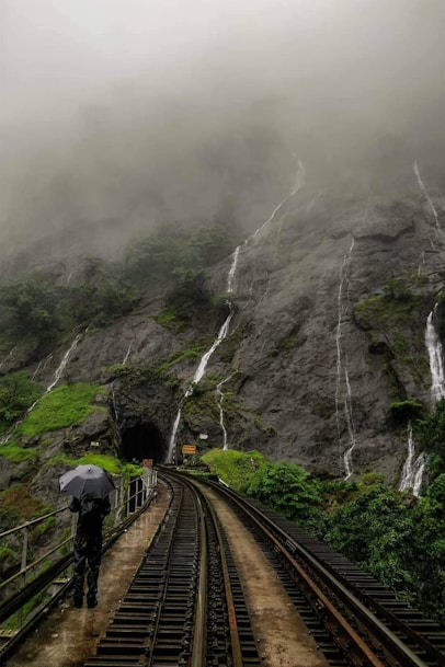 people walking on train rail near mountain