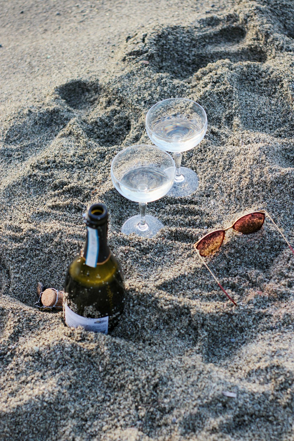 wine bottle with wine glass on sand
