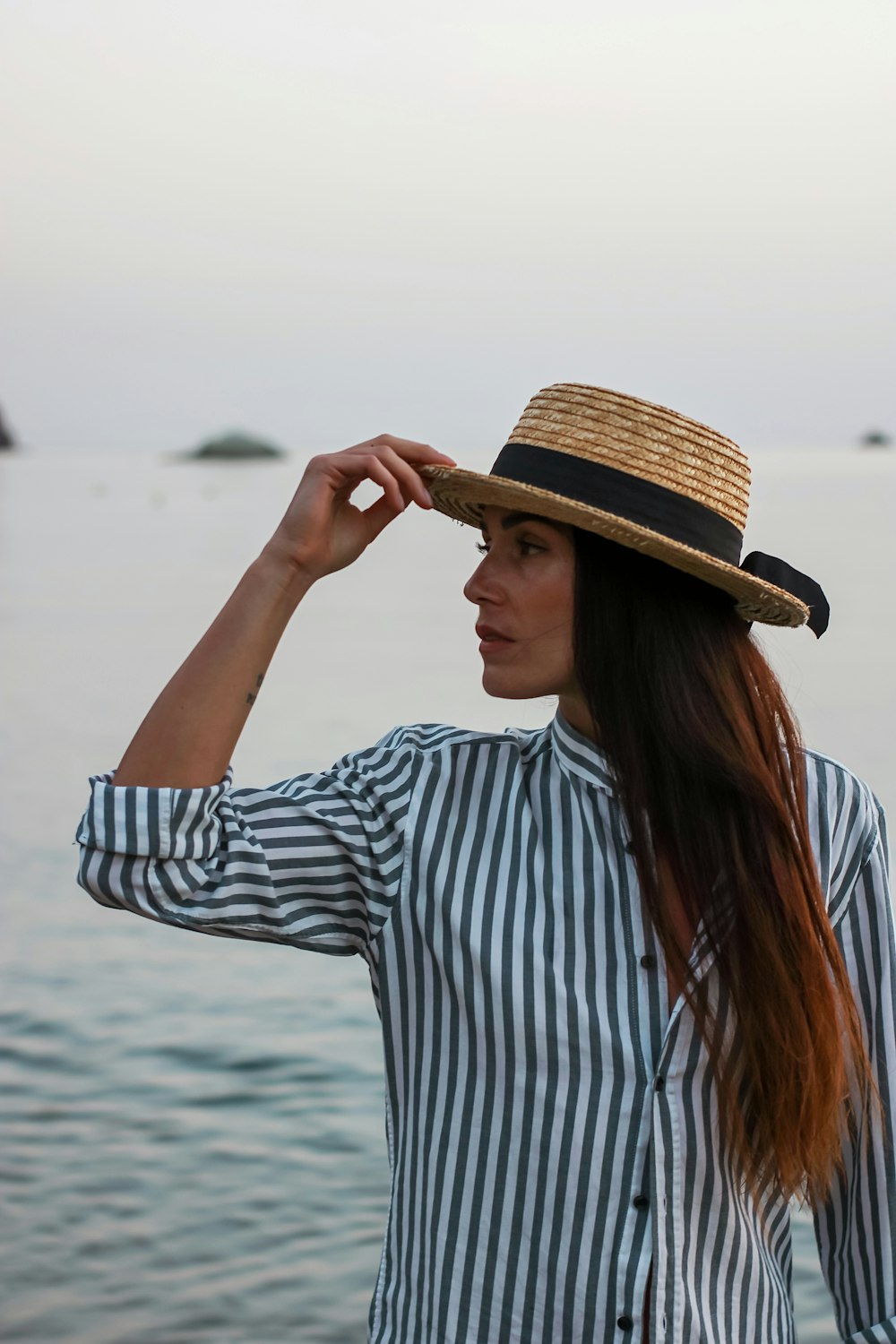 茶色の帽子をかぶった白と青の縞模様の長袖シャツを着た女性