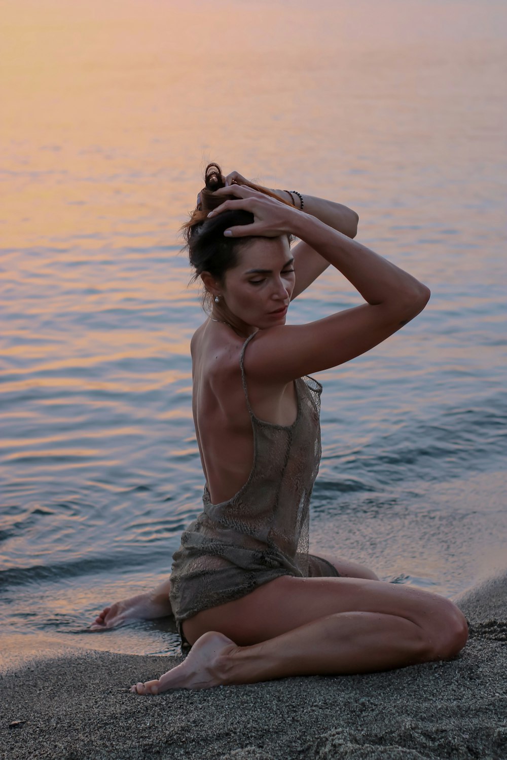 woman in white tank top and gray panty sitting on beach shore during daytime