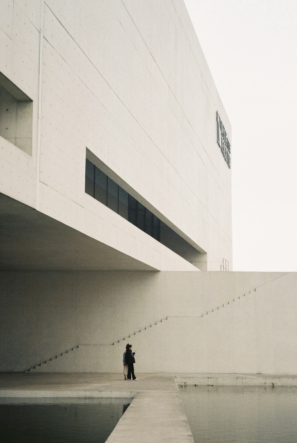man in black jacket walking on white concrete building
