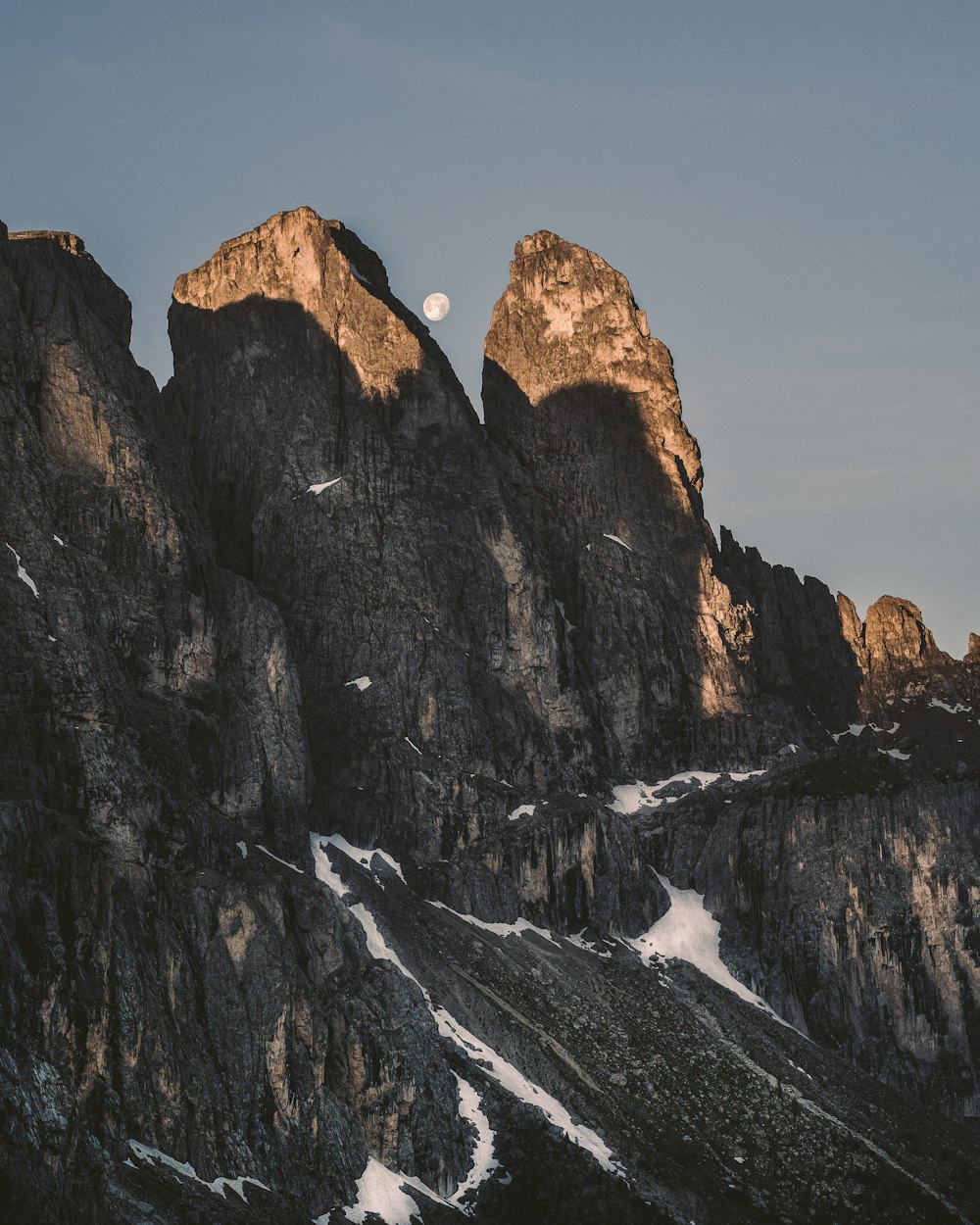 brauner felsiger Berg tagsüber mit Schnee bedeckt