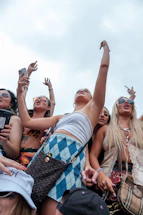 A vibrant photo of a group of young people charging their phones at a lively music festival with Voltvibe rental stations in the background.