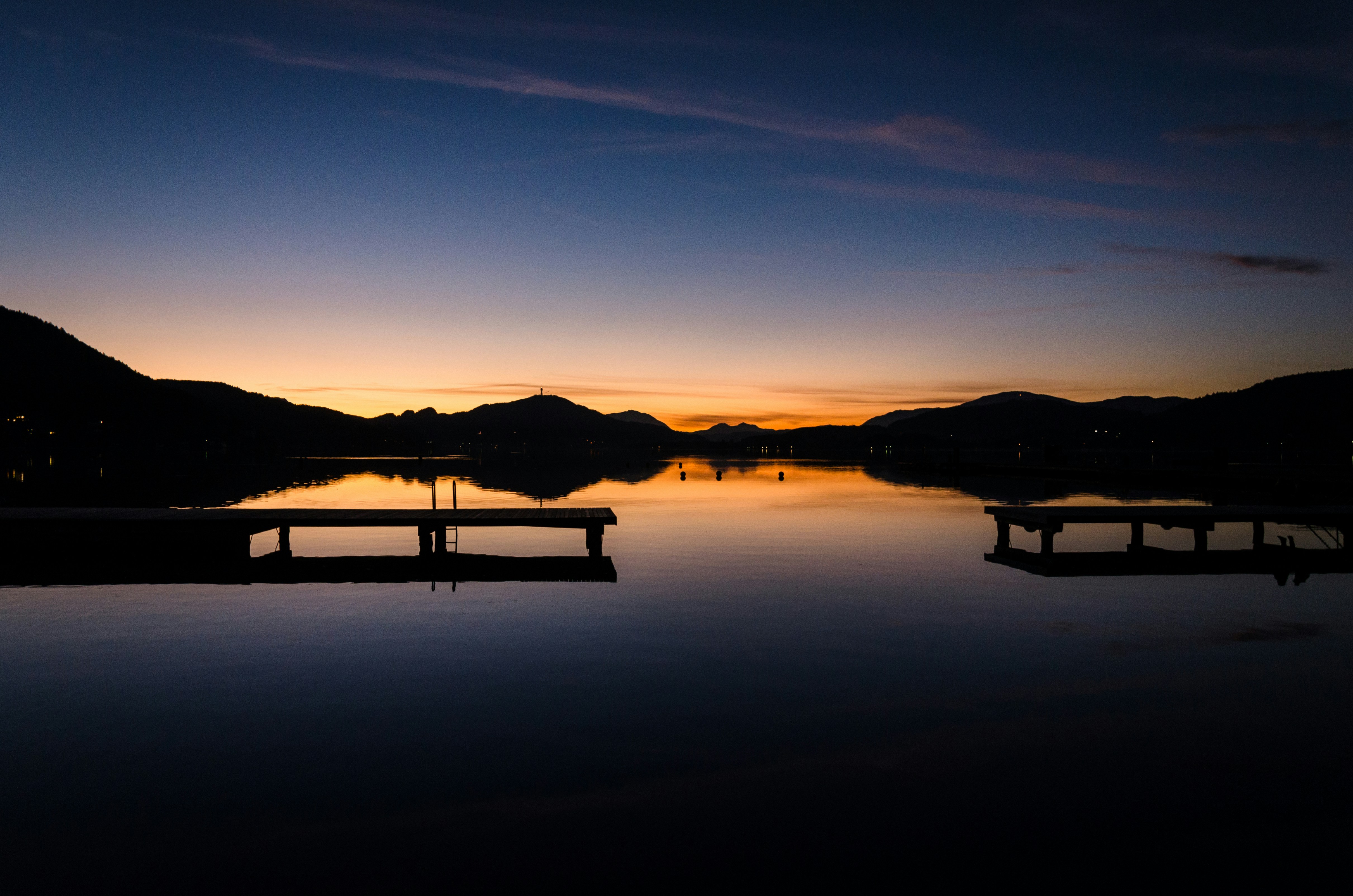 silhouette of mountain near body of water during sunset