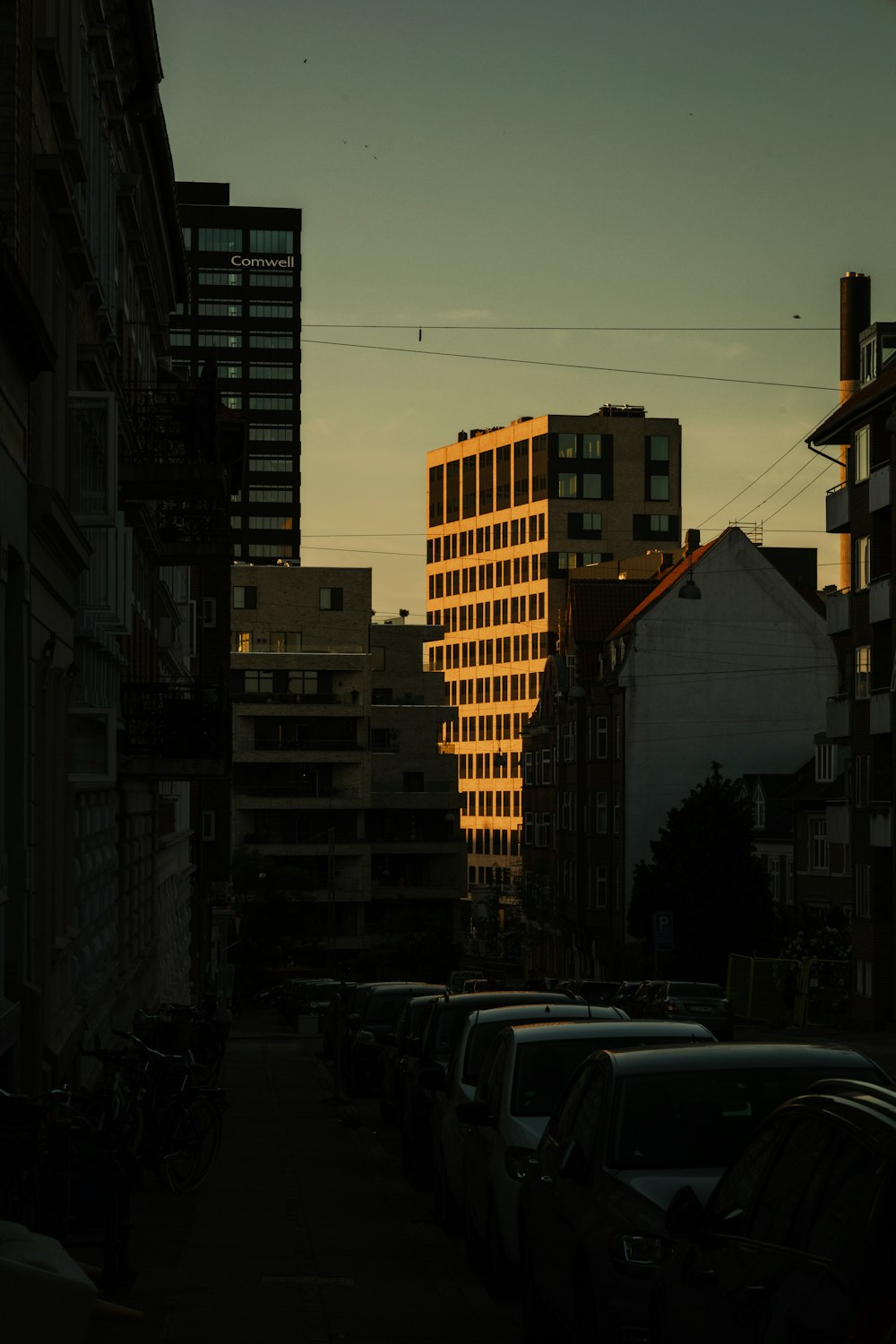 cars parked on side of road near high rise buildings during night time