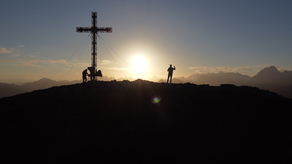 silhouette of person standing on top of mountain during sunset