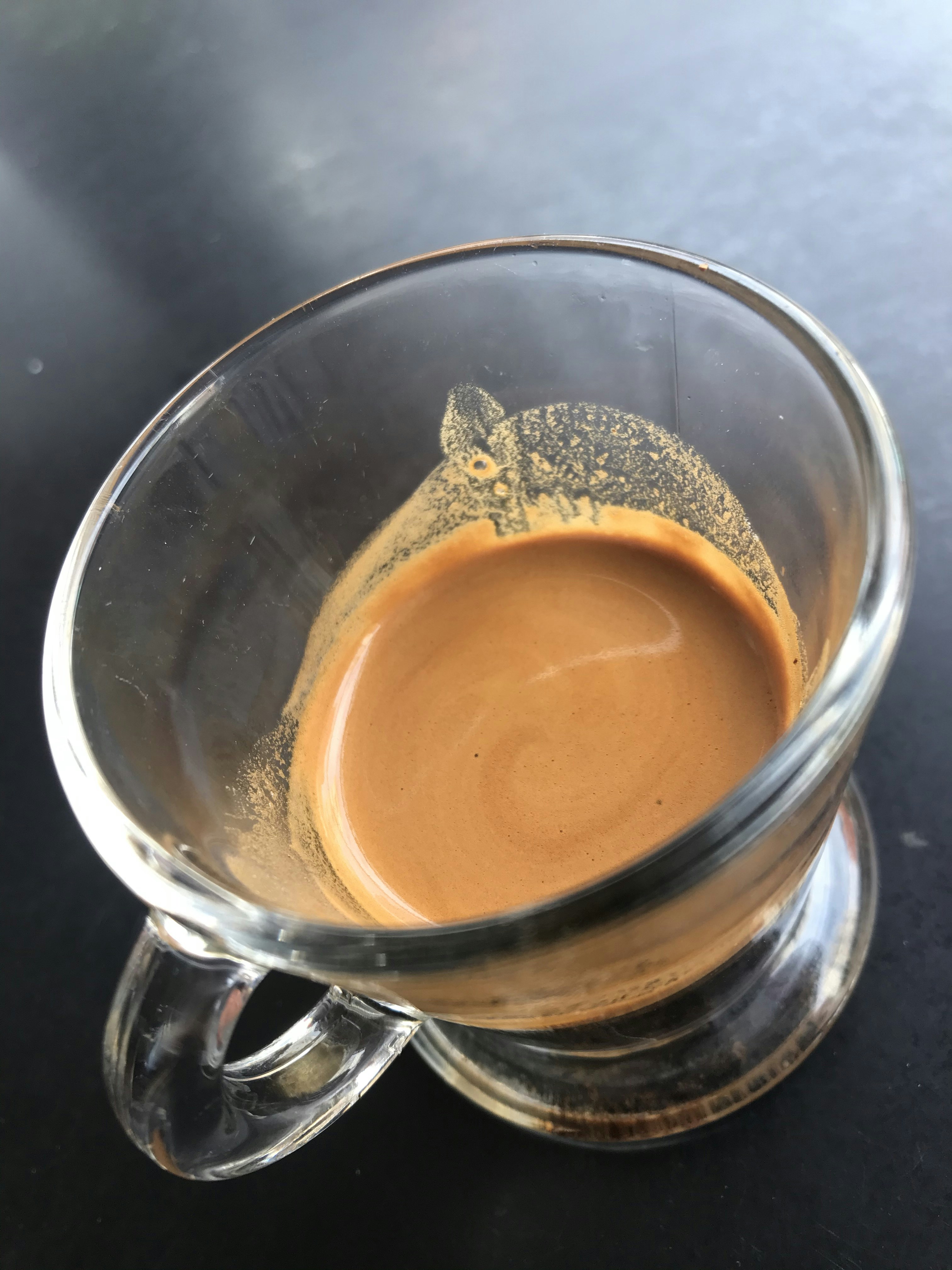 Rich espresso in a ceramic cup with golden crema on a dark wooden surface in warm café light