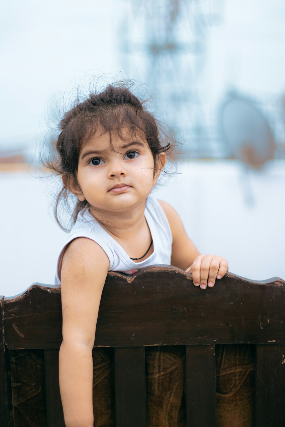 girl in white tank top sitting on brown wooden chair