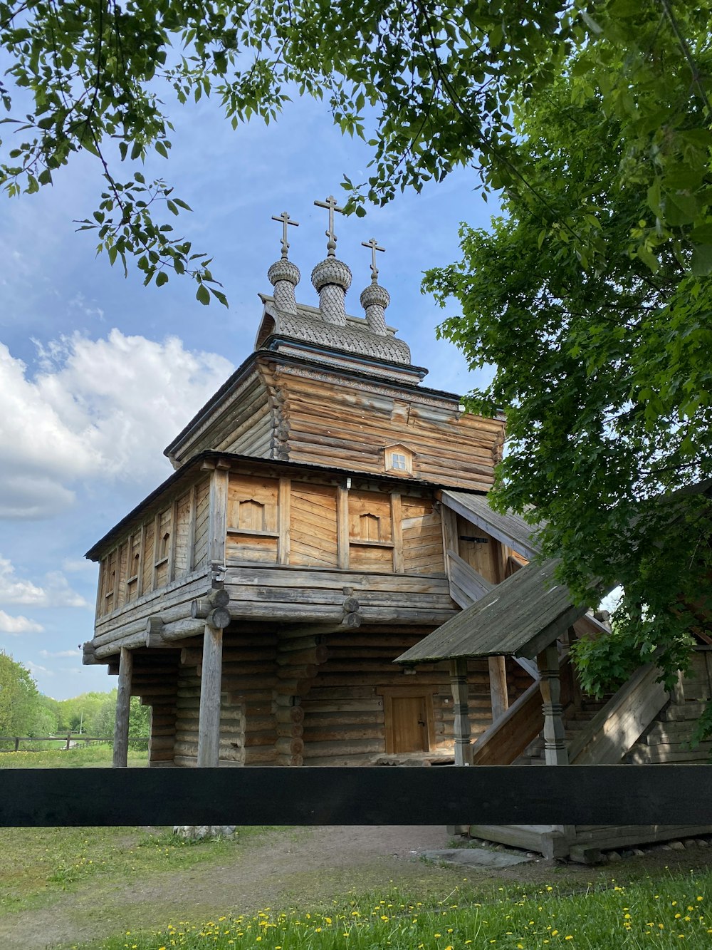 brown wooden house near green trees under blue sky during daytime